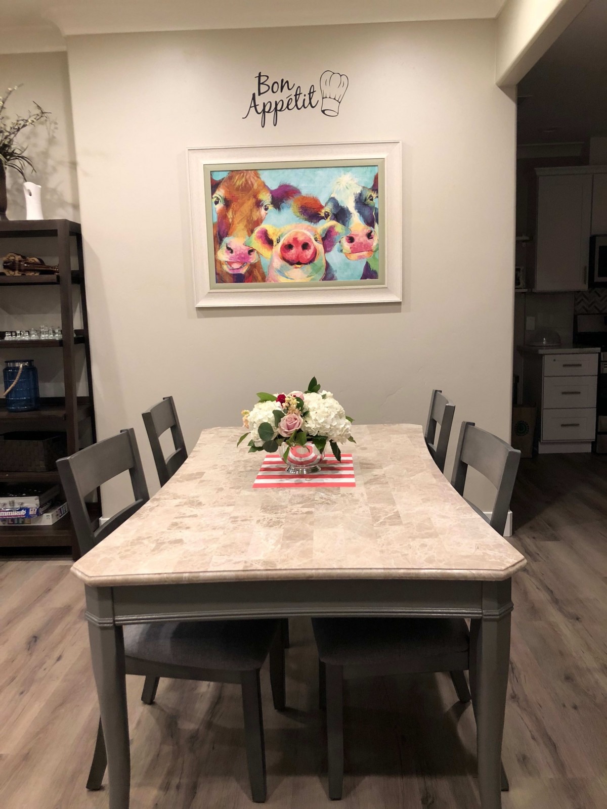 A cozy dining room featuring a rustic table with a floral centerpiece and whimsical animal artwork on the wall.