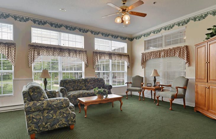 A cozy living room with floral-patterned furniture and large windows.