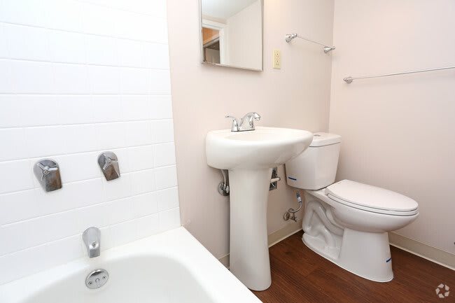 A clean and simple bathroom with a sink, toilet, bathtub, and mirror.