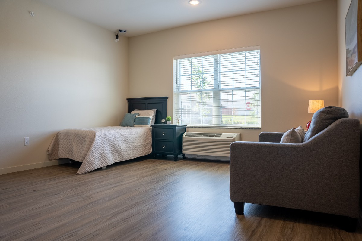 A minimalist and modern bedroom with a bed, sofa, and large window.