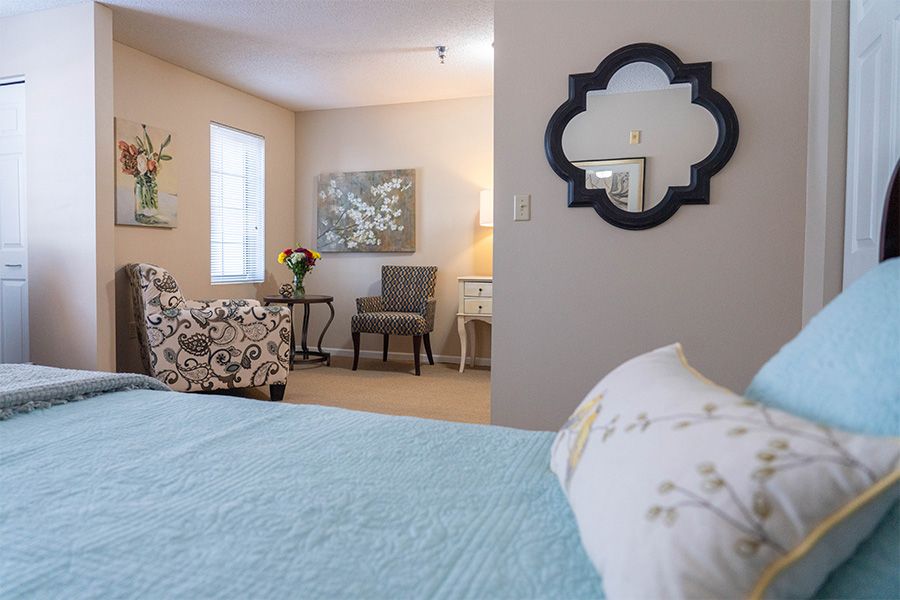 A cozy bedroom with a decorative mirror, armchair, and natural light.
