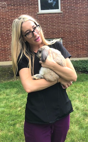 A woman gently holds a rabbit while enjoying a sunny day outdoors.