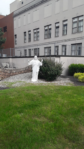 A serene white statue in a landscaped garden area.