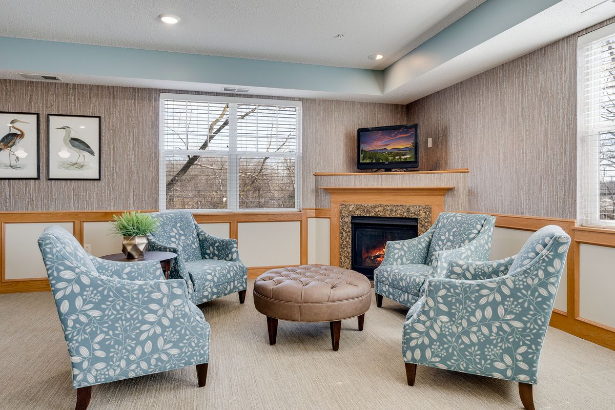 A cozy living room with patterned armchairs, a central coffee table, and a fireplace beneath a wall-mounted television.
