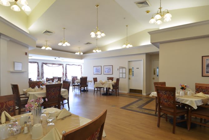 A spacious dining area with neatly arranged tables and chairs, illuminated by overhead lights.