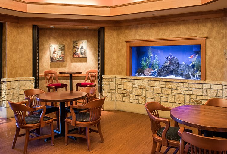 A cozy dining area in a restaurant featuring an aquarium built into the wall and wooden furniture.