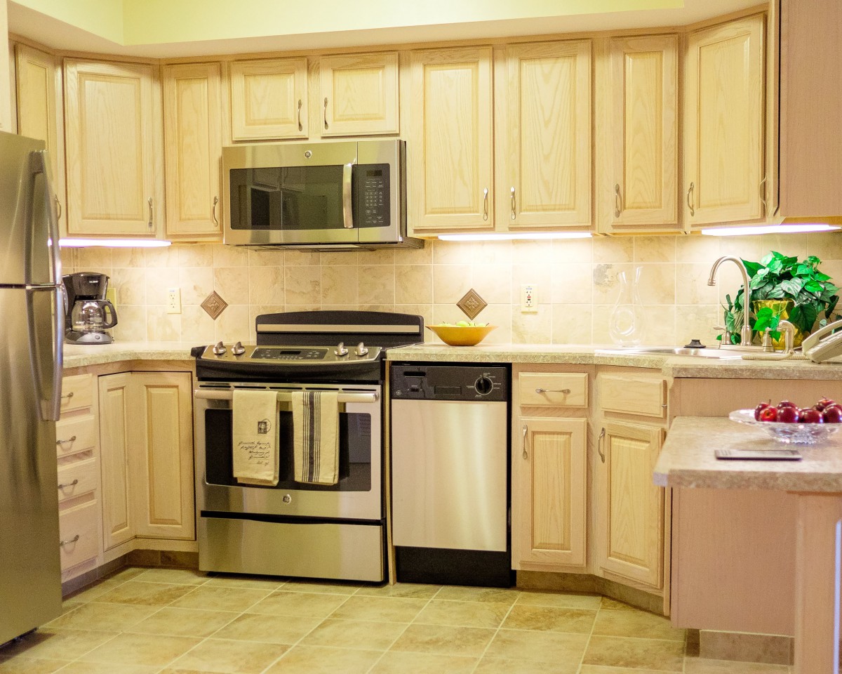 Modern kitchen with light wooden cabinets and stainless steel appliances.