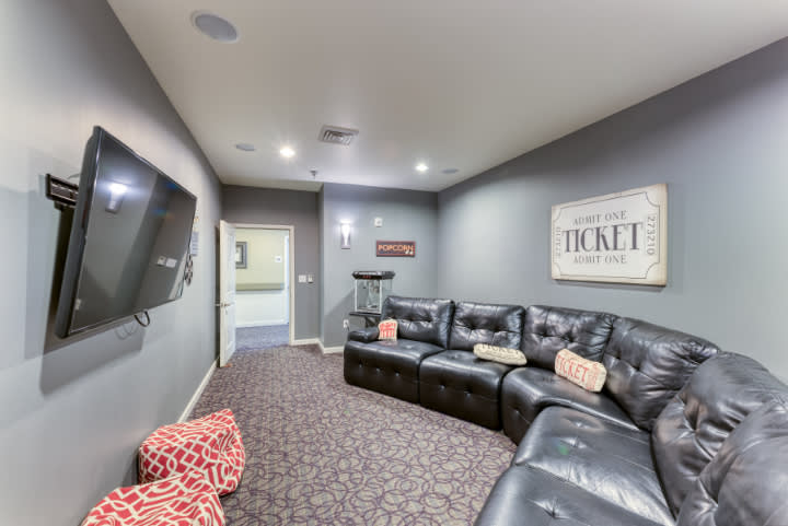A cozy home theater room with comfortable seating and a large television.