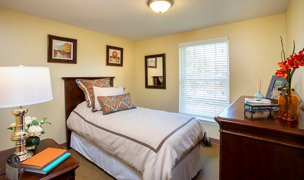 A cozy bedroom with a single bed, decorative pillows, and wall art.