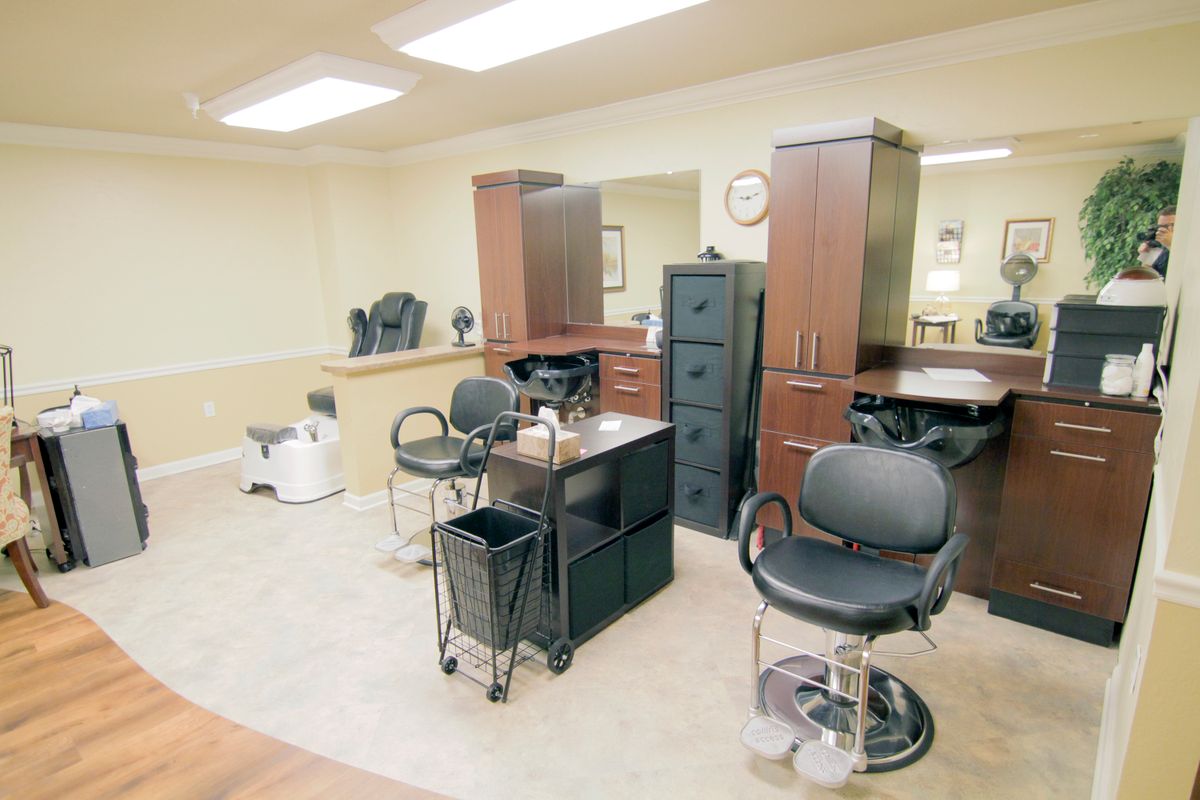 An empty hair salon interior featuring chairs, mirrors, and furniture.