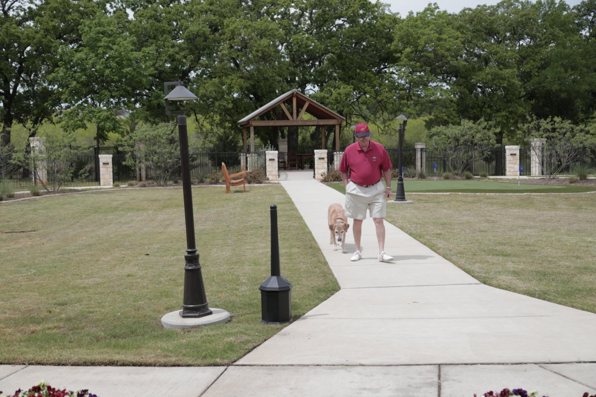 A man walking his dog along a pathway in a park.