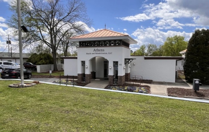 Entrance of a cemetery with a decorative arch and manicured lawn.