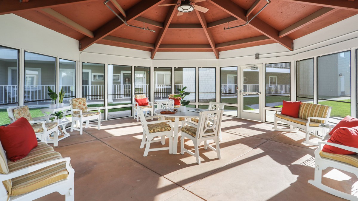 A cozy outdoor gazebo with comfortable seating and a table, perfect for enjoying natural light.