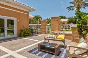 A cozy outdoor patio area featuring comfortable seating and vibrant cushions under a sunny sky.