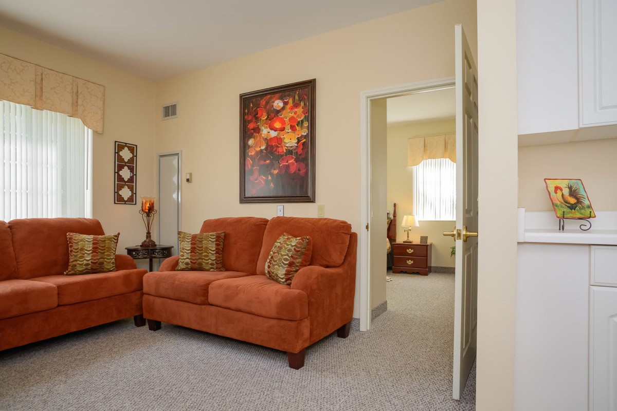 A cozy living room with orange sofas and vibrant artwork on the wall.