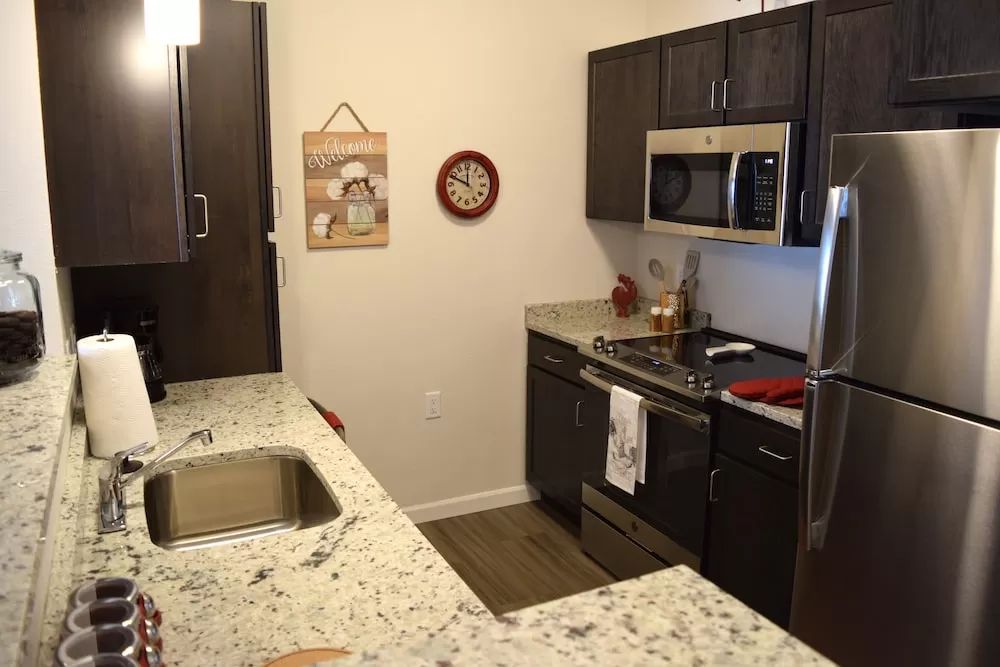A modern kitchen with granite countertops and stainless steel appliances.