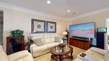 A cozy living room with a comfortable sofa, a large television, decorative wall art, and a wooden coffee table.