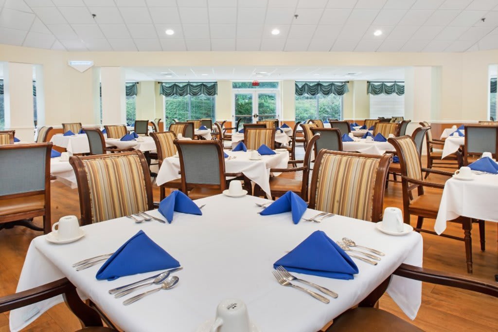 A well-arranged dining area with tables set with blue napkins.