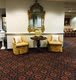 A cozy lobby seating area with two yellow chairs, a small table, and a decorative mirror on the wall.