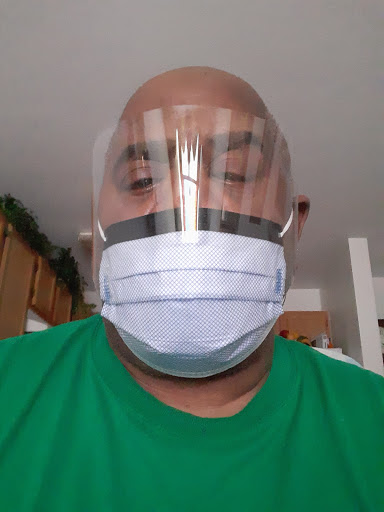 A person wearing a face shield and surgical mask indoors.