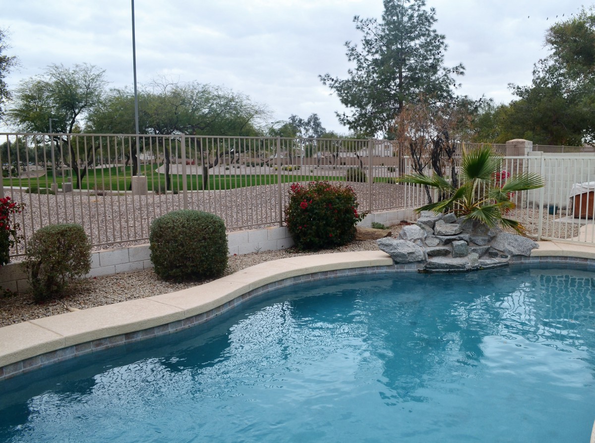 A serene outdoor pool area with surrounding greenery and a decorative rock feature.