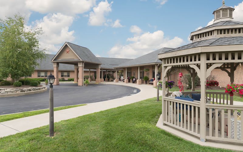 A scenic view of a building with a gazebo and well-maintained lawn under a cloudy sky.