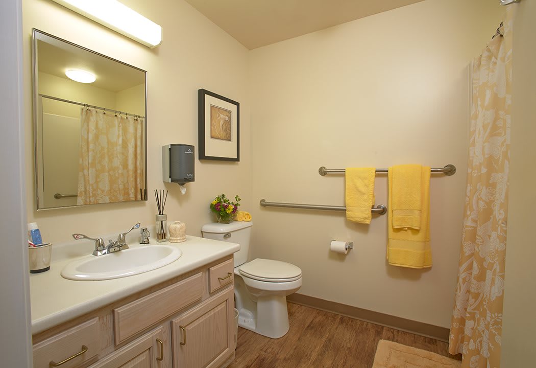 A clean and well-organized bathroom featuring yellow towels and simple decor.