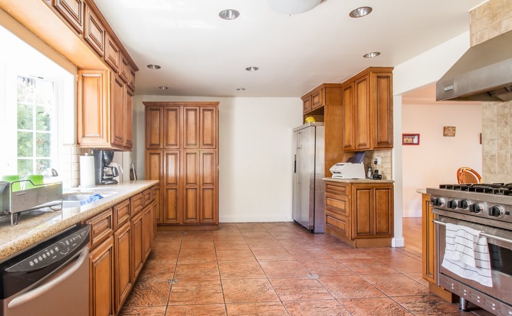 A spacious kitchen with wooden cabinets and tile flooring.
