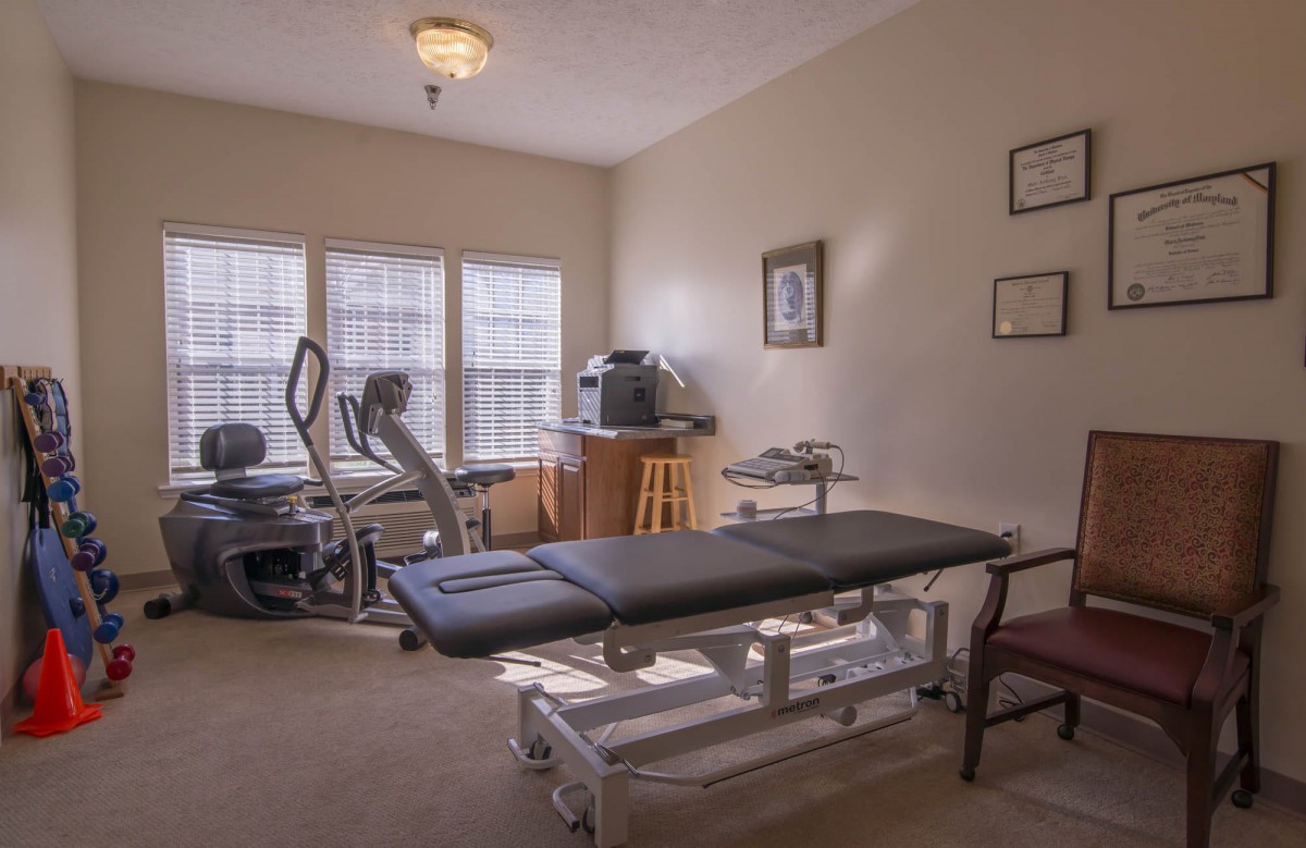 A therapy room equipped with exercise machines and a treatment table.