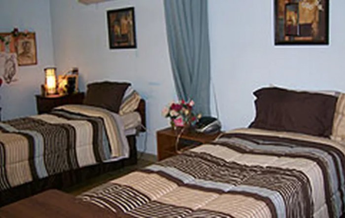 A cozy bedroom with two beds, decorated with striped bedding and floral accents.