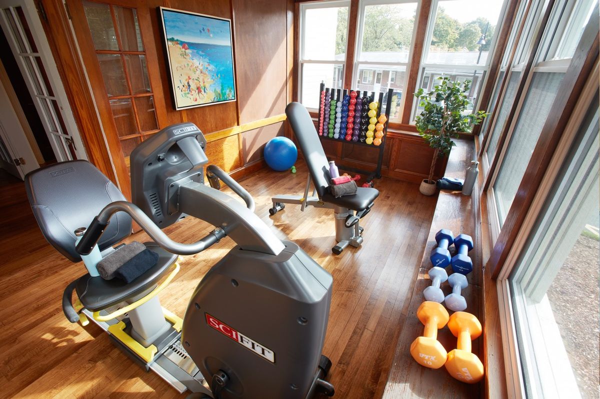 A cozy home gym with a treadmill, weights, and large windows for natural light.