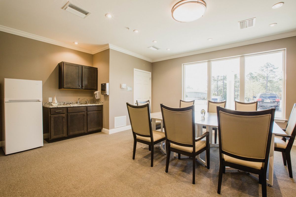A modern dining room with a table set and chairs, featuring large windows and elegant cabinetry.
