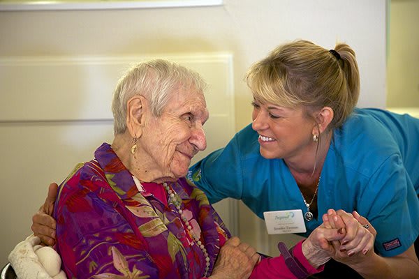 A caregiver shares a warm moment with an elderly woman.