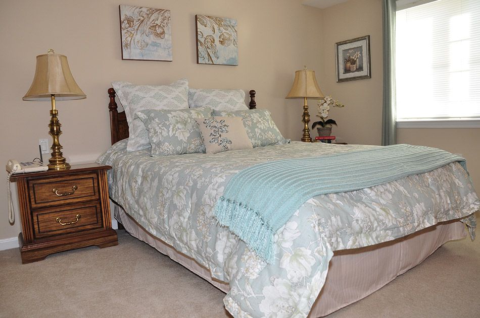 A cozy bedroom with a neatly made bed, decorative pillows, and calming artwork on the walls.