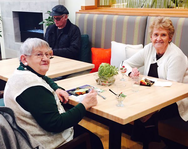 Two elderly women enjoying a meal together at a restaurant.