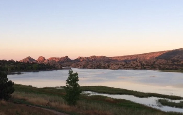 A tranquil lake at sunset with mountains in the background.