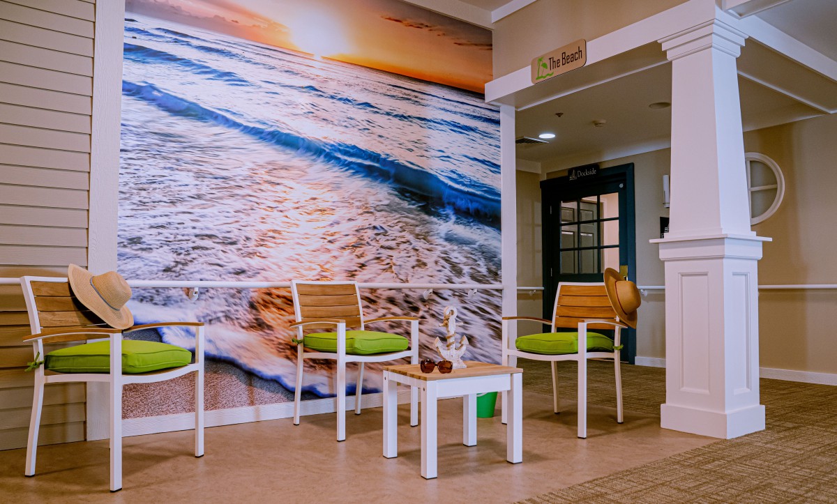 A cozy waiting area featuring green-cushioned chairs and a vibrant beach mural.