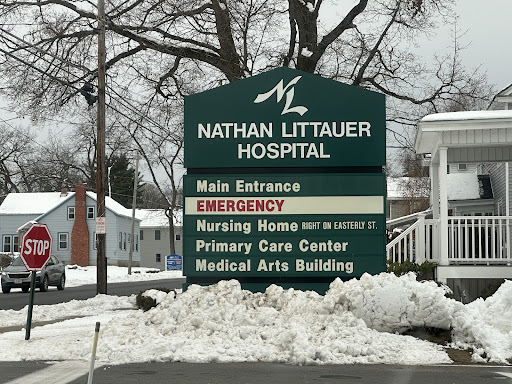 Signage for Nathan Littauer Hospital, indicating the main entrance and emergency services amidst snowy conditions.