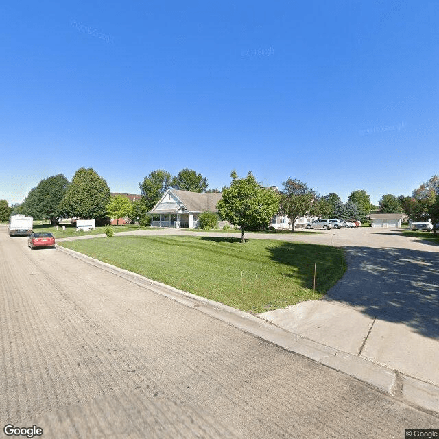 A quiet suburban street lined with houses and trees under a clear blue sky.