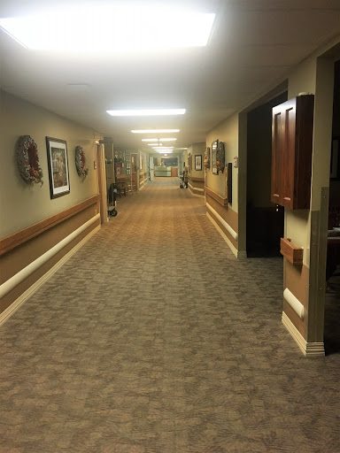 A well-lit hallway featuring patterned carpet and decorative wall art.