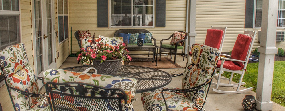 A cozy patio setup with floral-cushioned chairs, a table, and vibrant flowers.