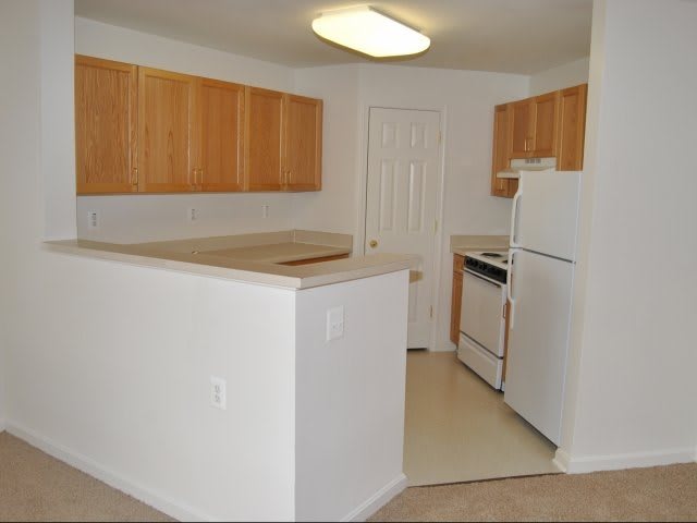 A modern kitchen with wooden cabinets and white appliances.