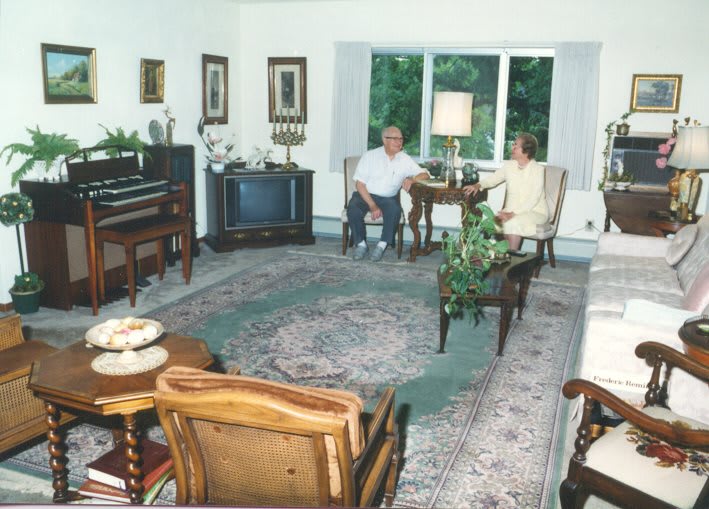 Two people sitting in a cozy living room with classic furniture and decor.