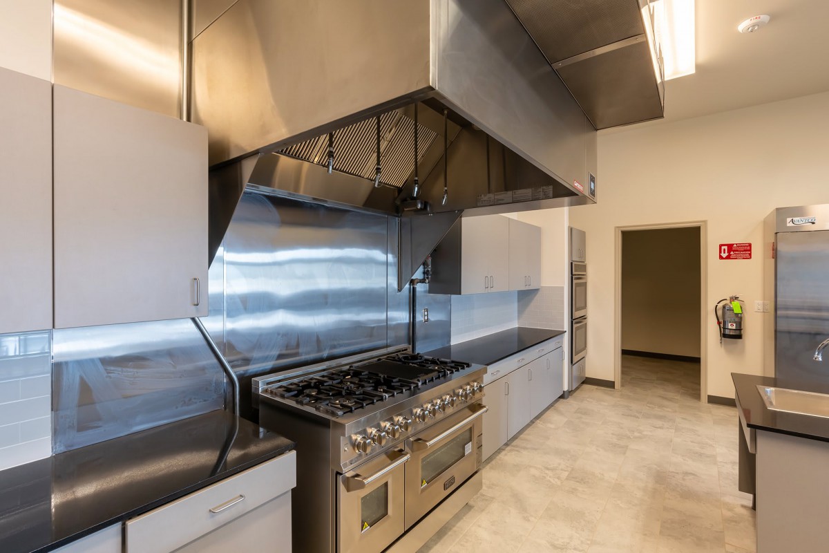 An industrial kitchen with a stainless steel oven and vent hood.