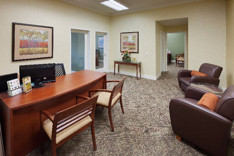 A view of a professional office space with a desk, chairs, and decorative artwork.