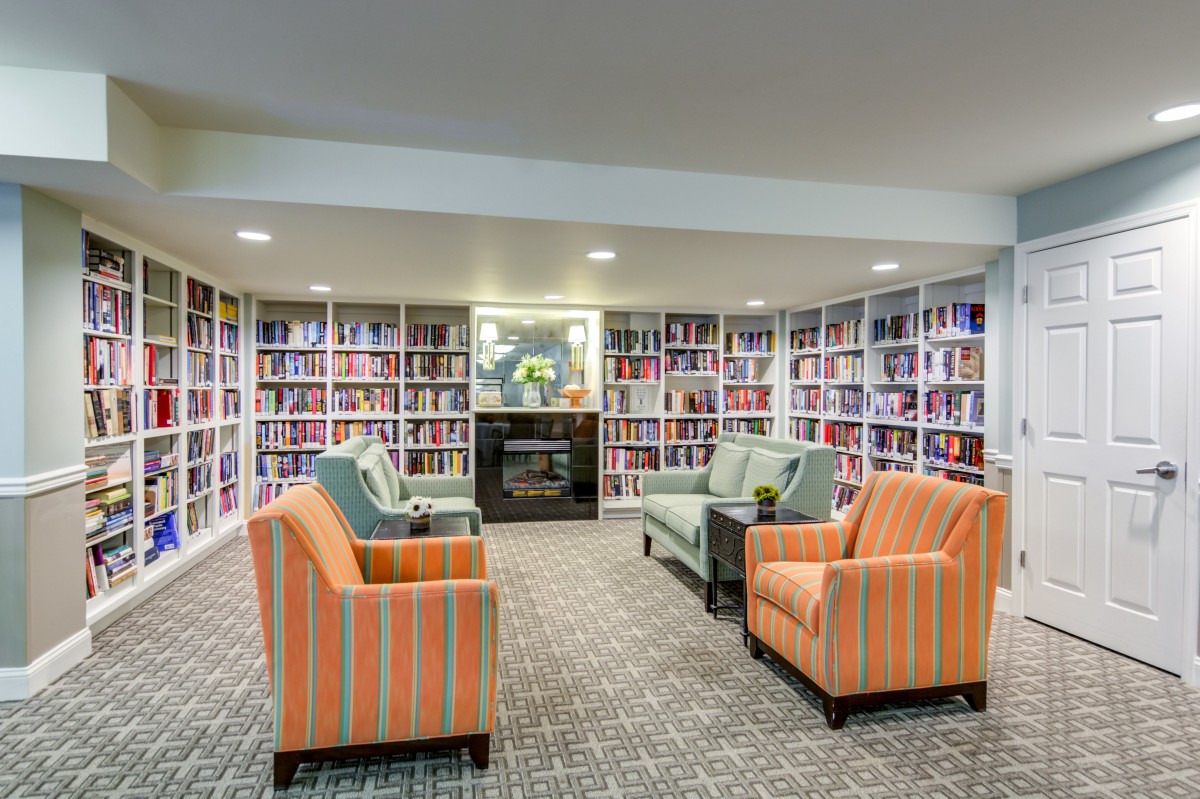 A cozy library with bookshelves and comfortable armchairs arranged around a seating area.