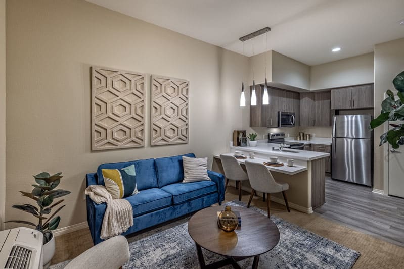 A modern living room with an open kitchen and dining area, featuring stylish furniture and decor.