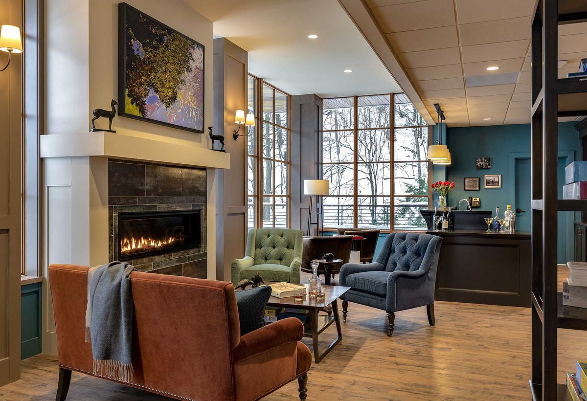 A cozy living room with a fireplace, seating area, and large windows.