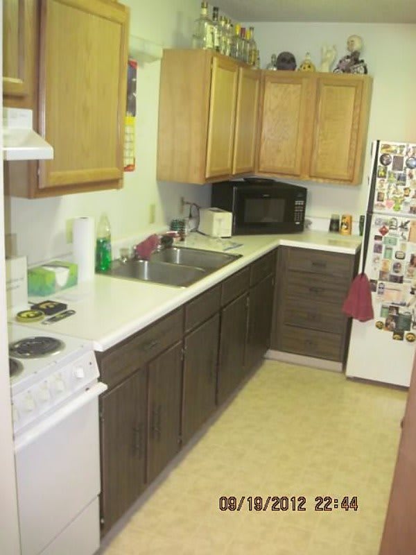 A cozy kitchen with wooden cabinets, a microwave, and a fridge adorned with magnets.