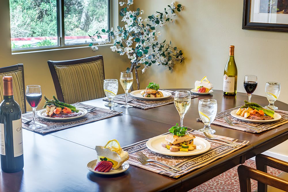 An elegantly set dining table with gourmet dishes and wine glasses, ready for a fine dining experience.